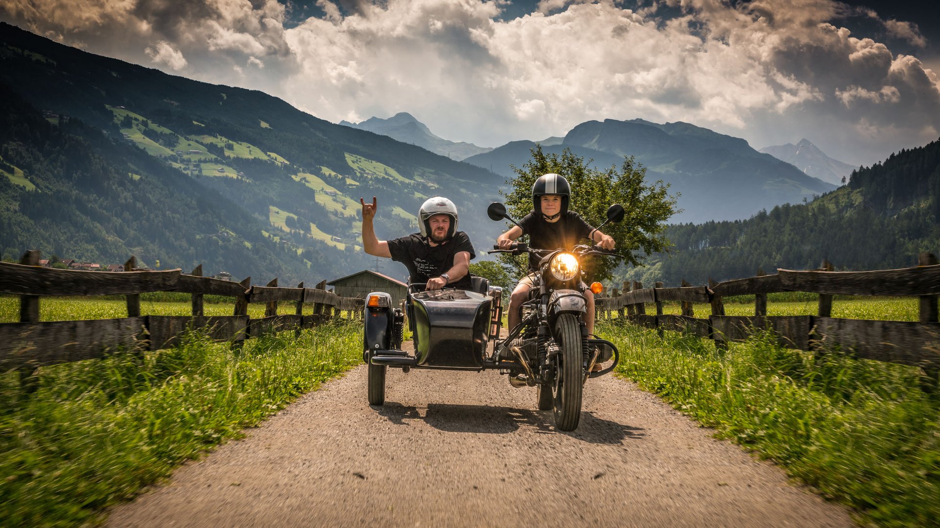 Zwei Personen fahren Motorrad mit Beiwagen auf Landstraße vor Berglandschaft (© Moppetfoto.de)